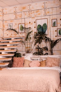 Büyük yumuşak bir yatak, merdivenler, modern bir iç mekanda bitkiler. Güzel modern yatak odası