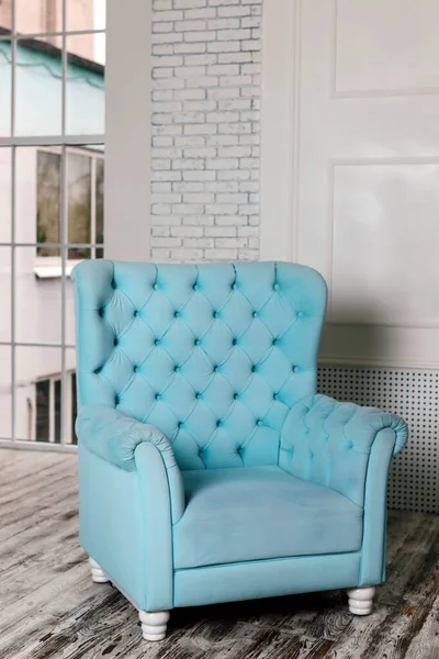 Comfortable soft blue armchair in a bright interior. High quality photo