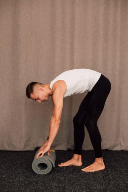 Genç bir atlet yoga minderi serer. Yüksek kalite fotoğraf