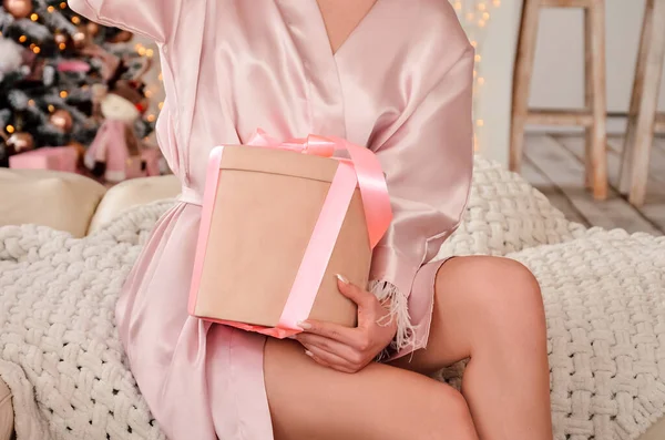 Pink gift in the hands of a young sexy girl in a bathrobe. High quality photo