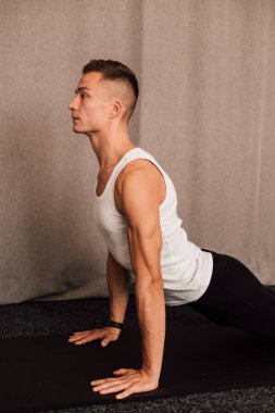 Yan görüş. Adam elleri dinlenirken yerde yatar. Sporcuların kollarındaki kaslar açıkça görülüyor.