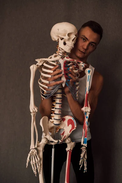 Mężczyzna Trzyma Rękach Nogę Szkieletu Wskazuje Palcem Nią Wysokiej Jakości — Zdjęcie stockowe
