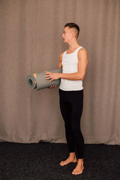 A man sports coach holds a yoga mat in his hands. High quality photo