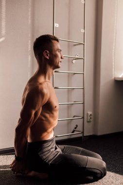 Çıplak gövdeli bir adam yerde oturuyor. Atletik vücut. Spor Yogası Egzersizleri. Yüksek kalite fotoğraf