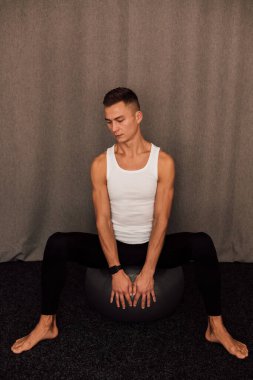 Genç bir sporcu spor yaparken bir fitbol topuna oturur. Spor Yoga Zindeliği. Yüksek kalite fotoğraf