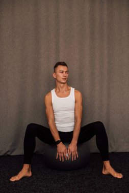 Genç bir sporcu spor yaparken bir fitbol topuna oturur. Spor Yoga Zindeliği. Yüksek kalite fotoğraf