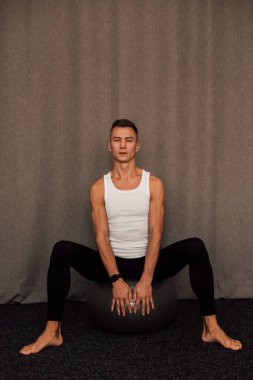 Genç bir sporcu spor yaparken bir fitbol topuna oturur. Spor Yoga Zindeliği. Yüksek kalite fotoğraf