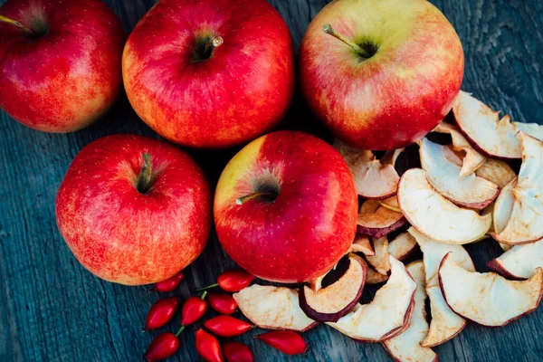 Apples, dried apples and rose hips lie on a dark wooden table Autumn. High quality photo