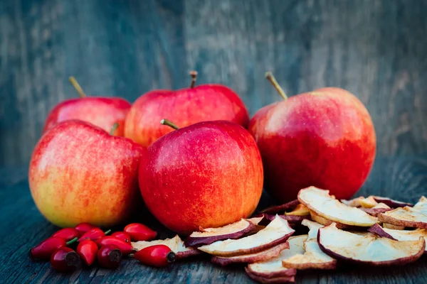 Apples, dried apples and rose hips lie on a dark wooden table Autumn. High quality photo