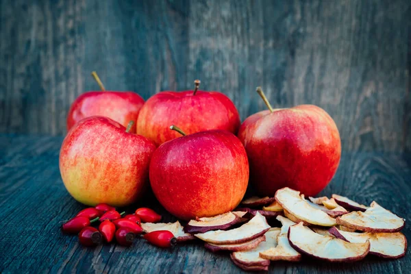 Apples, dried apples and rose hips lie on a dark wooden table Autumn. High quality photo