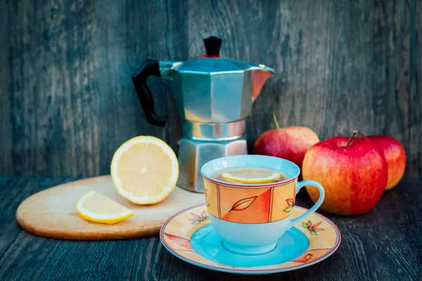 A cup of tea, rose hips, apples and a kettle on the table. Vitamins, disease prevention. High quality photo