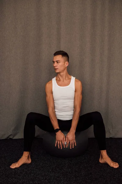 Genç bir sporcu spor yaparken bir fitbol topuna oturur. Spor Yoga Zindeliği. Yüksek kalite fotoğraf