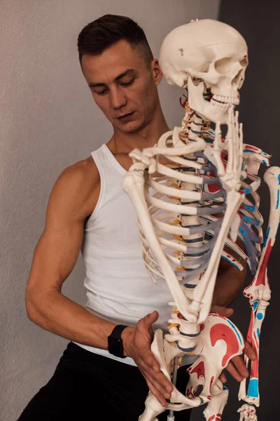 一个穿着白色T恤的男人研究人体骨骼的结构 高质量的照片 — 图库照片