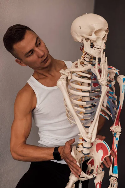 一个穿着白色T恤的男人研究人体骨骼的结构 高质量的照片 — 图库照片