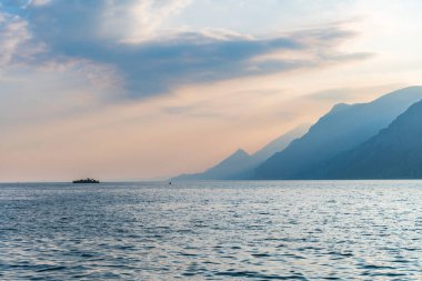 Punta San Vigilio, İtalya, sakin deniz suyu, dağlar, gökyüzü ve tekne 