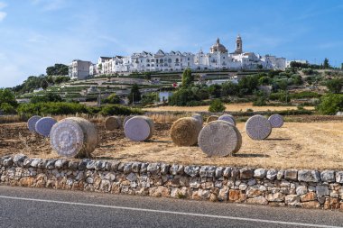 Locorotondo, İtalya - 4 Temmuz 2021: Arka planda şehir bulunan samanlıklardan oluşan sanat sergisi