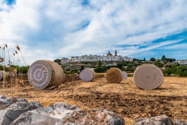 Locorotondo, İtalya - 4 Temmuz 2021: Arka planda şehir bulunan samanlıklardan oluşan sanat sergisi