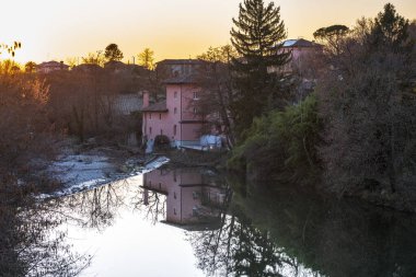Cormons, İtalya 'da Komün, Friuli-Venezia Giulia, nehir kanalı ve ağaçlar, köyde gün batımı ve evler. 