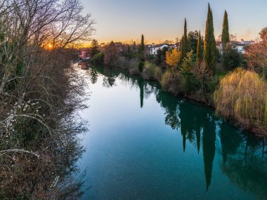 Cormons, İtalya 'da Komün, Friuli-Venezia Giulia, nehir kanalı ve ağaçlar, köyde günbatımı 