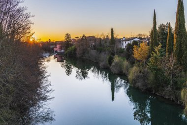 Cormons, İtalya 'da Komün, Friuli-Venezia Giulia, nehir kanalı ve ağaçlar, köyde günbatımı 