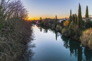 Cormons, İtalya 'da Komün, Friuli-Venezia Giulia, nehir kanalı ve ağaçlar, köyde günbatımı 