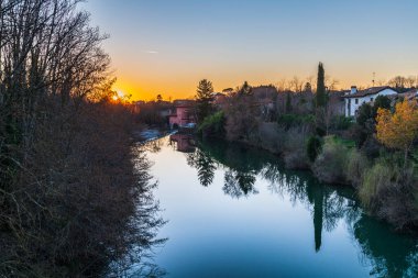 Cormons, İtalya 'da Komün, Friuli-Venezia Giulia, nehir kanalı ve ağaçlar, köyde günbatımı 