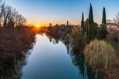 Cormons, İtalya 'da Komün, Friuli-Venezia Giulia, nehir kanalı ve ağaçlar, köyde günbatımı 