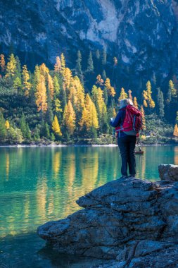 Sırt çantalı bir yürüyüşçü dağdaki gölde yürüyüş yapıyor.