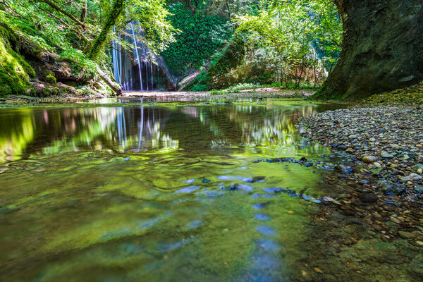 Waterfall surrounded by greenery. Acquacaduta. Friuli, Italy