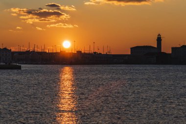 Trieste Audace rıhtımından gün batımı. Suyun üzerindeki ateş renkleri. İtalya