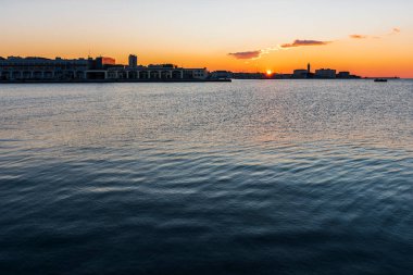 Trieste Audace rıhtımından gün batımı. Suyun üzerindeki ateş renkleri. İtalya