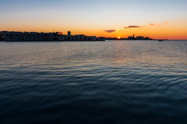 Trieste Audace rıhtımından gün batımı. Suyun üzerindeki ateş renkleri. İtalya