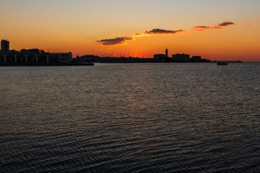 Trieste Audace rıhtımından gün batımı. Suyun üzerindeki ateş renkleri. İtalya