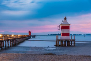 İtalya 'da deniz feneri olan sahil. Gün batımında Lignano tatil köyü.