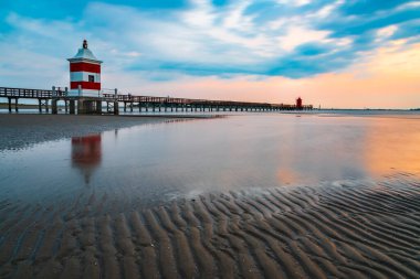 İtalya 'da deniz feneri olan sahil. Gün batımında Lignano tatil köyü.
