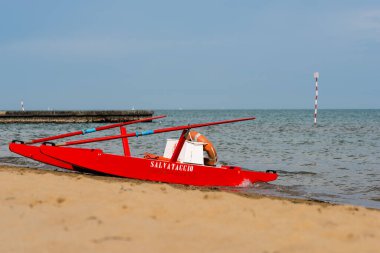 Sahildeki kırmızı tekne doğal arka planda.