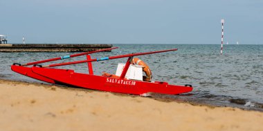 Sahildeki kırmızı tekne doğal arka planda.