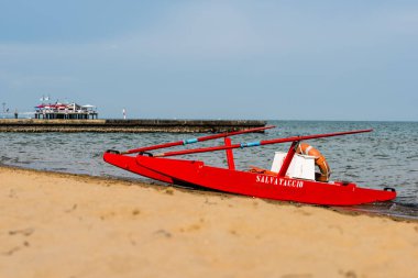 Sahildeki kırmızı tekne doğal arka planda.