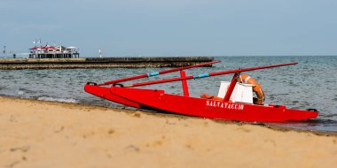 Sahildeki kırmızı tekne doğal arka planda.