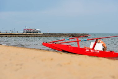 Sahildeki kırmızı tekne doğal arka planda.