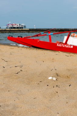Sahildeki kırmızı tekne doğal arka planda.