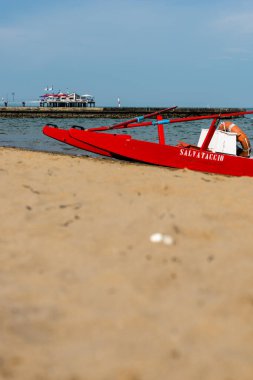 Sahildeki kırmızı tekne doğal arka planda.