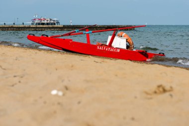 Sahildeki kırmızı tekne doğal arka planda.