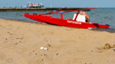 Sahildeki kırmızı tekne doğal arka planda.