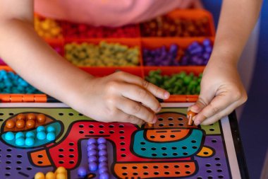 Çocuklar yakın çekim yapar. Çocuk bir mozaik toplar. Çocuk oyun sahasına mozaiğin bir parçasını yerleştirir..