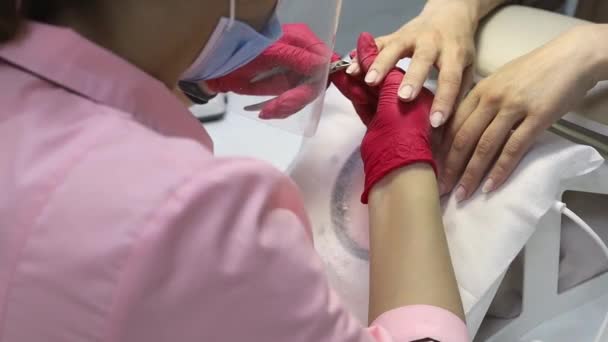 Una mujer se sienta en una mesa y le da una manicura al cliente.Cortauñas — Vídeos de Stock