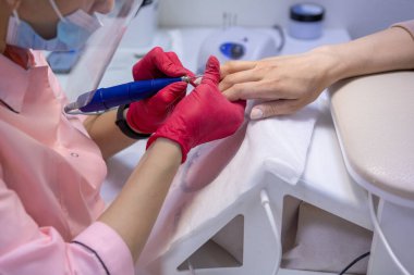 Bir kadın masaya oturur ve müşteriye manikür yapar. Kadın manikürü.