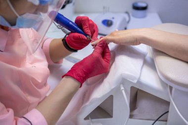 Bir kadın masaya oturur ve müşteriye manikür yapar. Kadın manikürü.