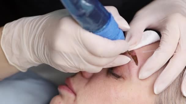 The master makes permanent eyebrow makeup with a needle tattoo machine — Stock Video