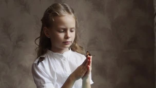 Dívka se podívá na motýla na své ruce. — Stock video